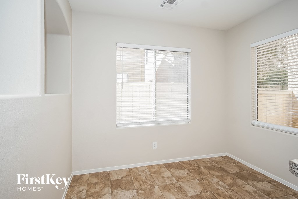 the living room of a home with white walls and a large window