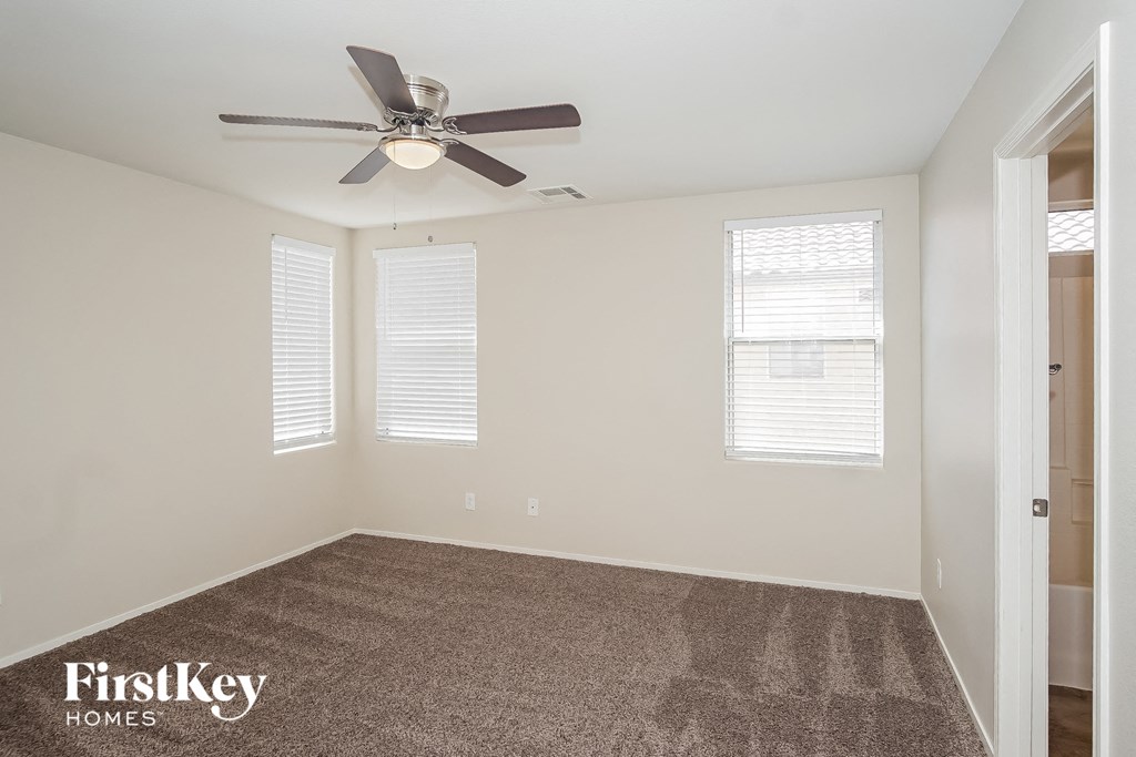 a living room with a ceiling fan and a carpet