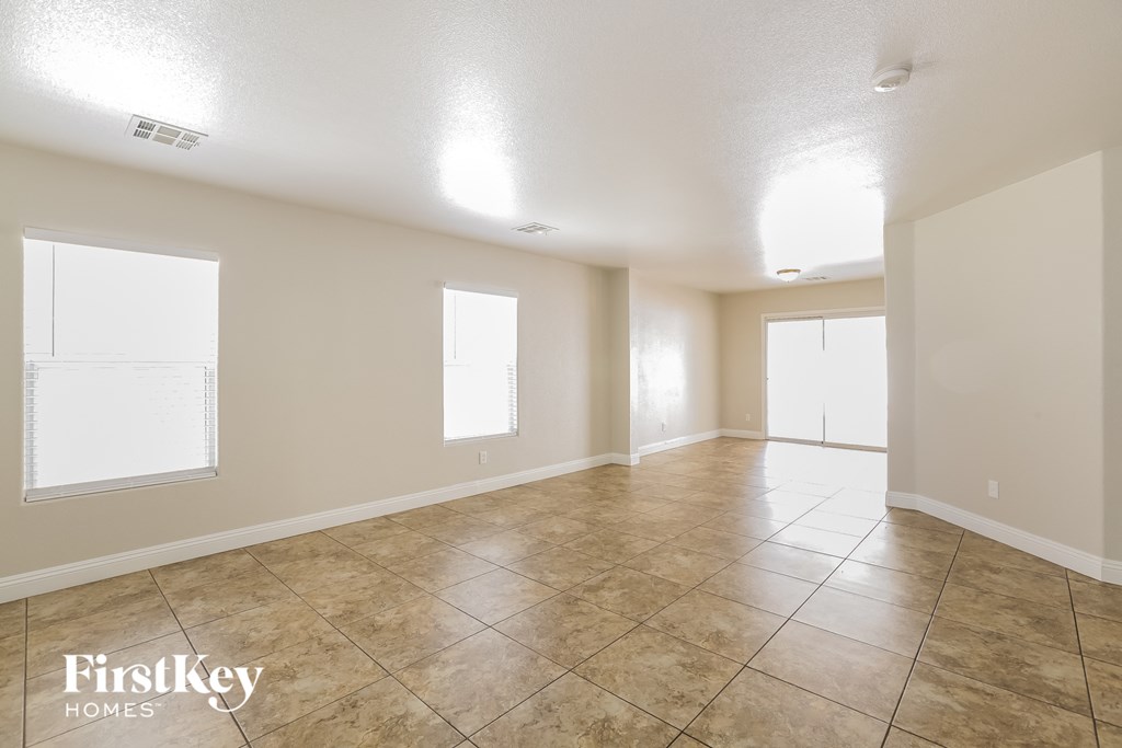 a spacious living room with tile floors and white walls