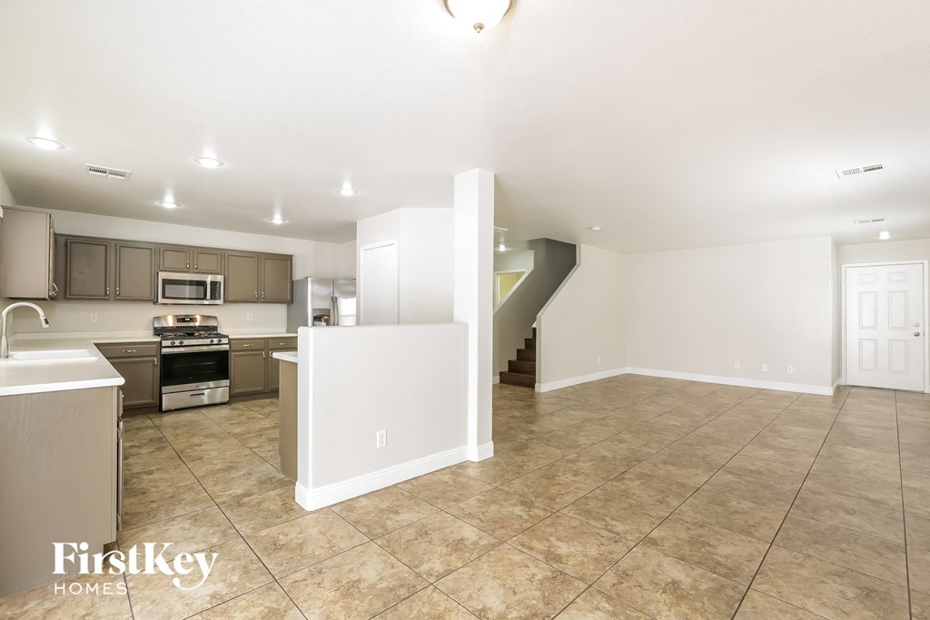 an open kitchen and living room with tile flooring and stainless steel appliances