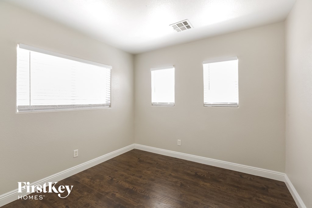 the living room with wood floors and three windows