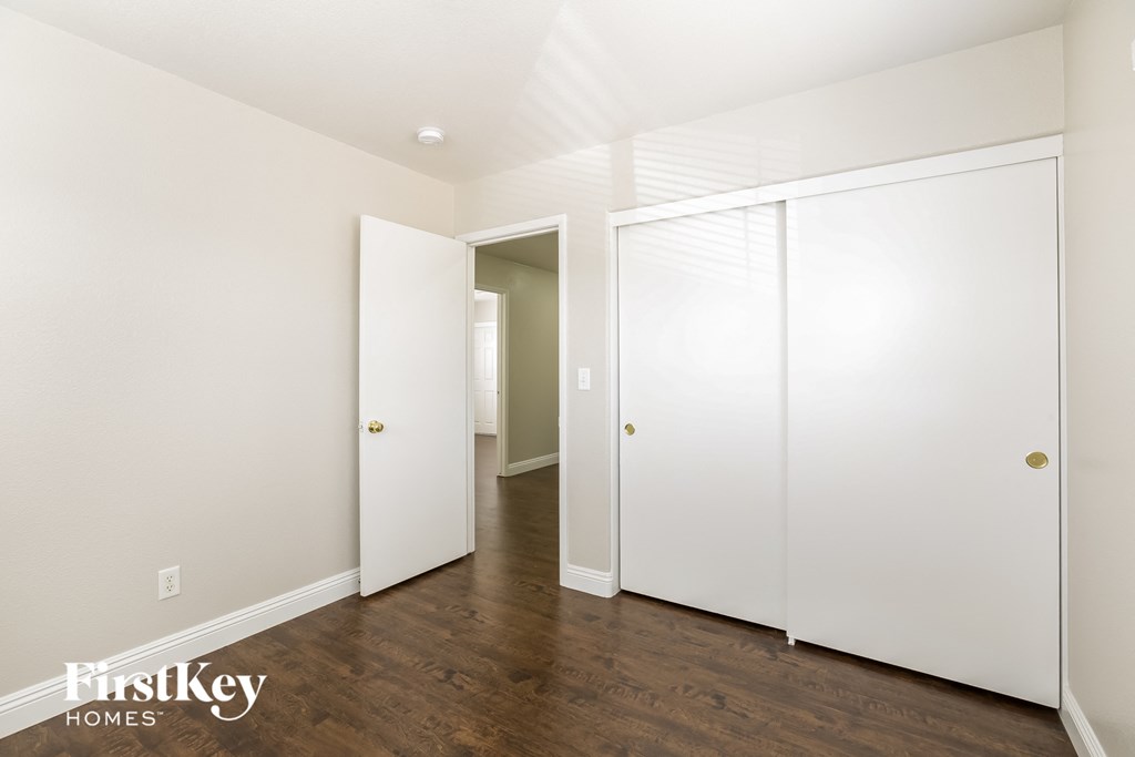 a white bedroom with two white closets and a wood floor