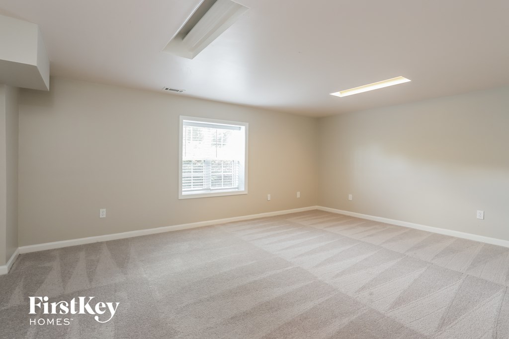the spacious living room with white carpet and a window