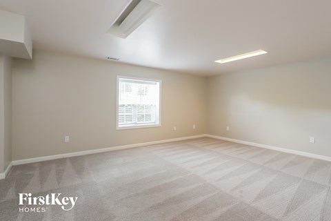 the spacious living room with white carpet and a window