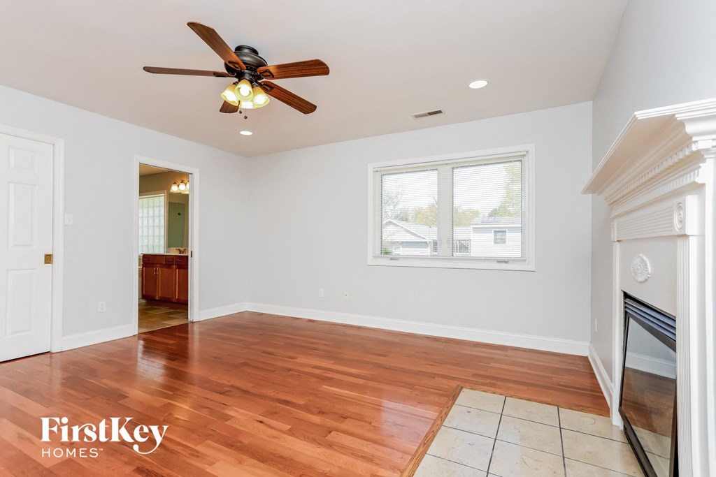 an empty living room with wood floors and a ceiling fan