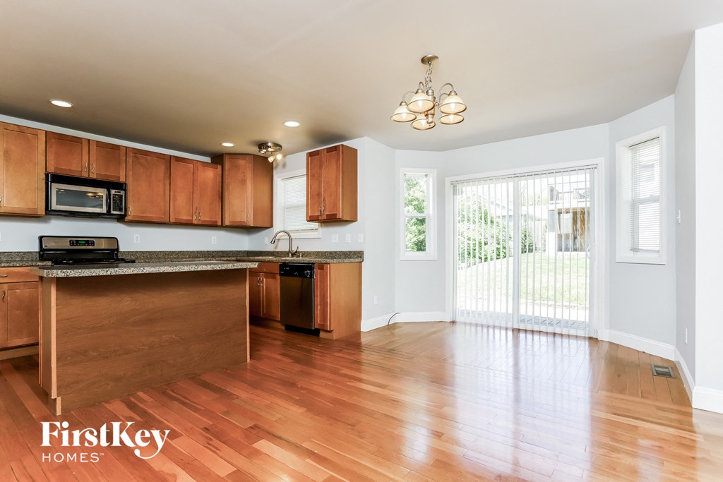 an empty kitchen with wooden cabinets and a door to a balcony