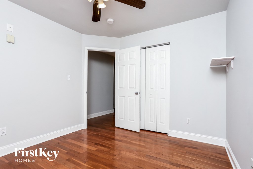 a bedroom with white walls and wood floors and a closet