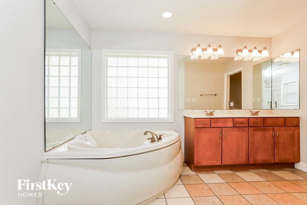 a bathroom with a large tub and a sink and a mirror
