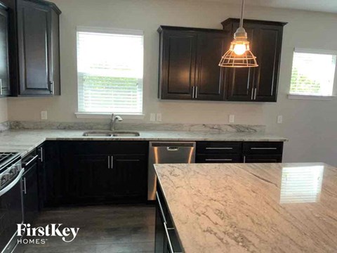 A kitchen with black cabinets and a marble countertop.