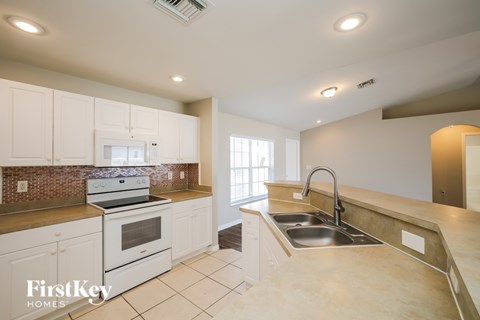 A kitchen with white cabinets and a stove top oven.