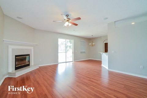 an empty living room with a fireplace and a ceiling fan