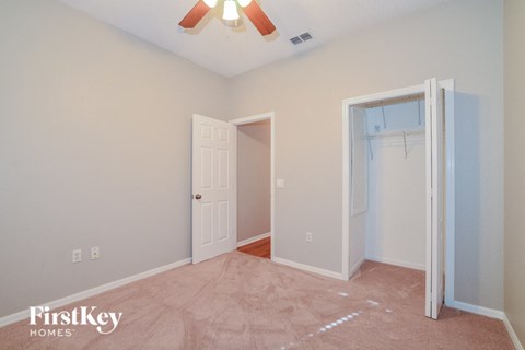 a bedroom with a closet and a white door and a ceiling fan