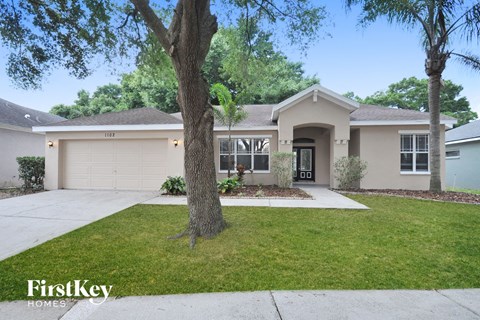 the front of a house with a lawn and trees