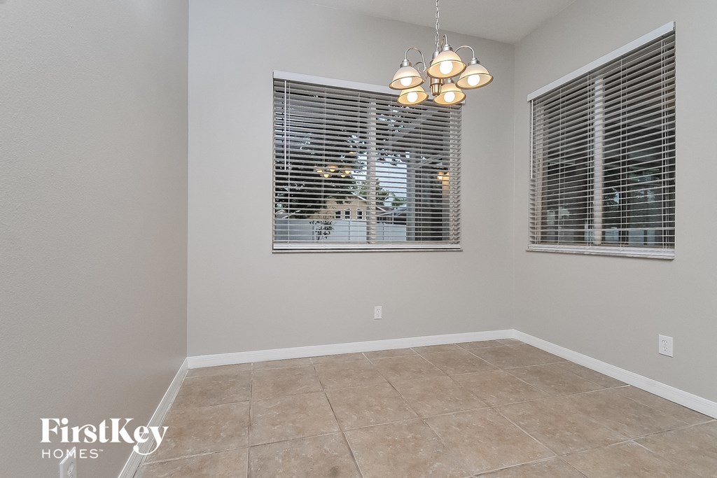 the living room of a house with two windows and a tiled floor