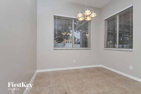 the living room of a house with two windows and a tiled floor