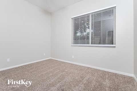 a bedroom with a window and a carpeted floor