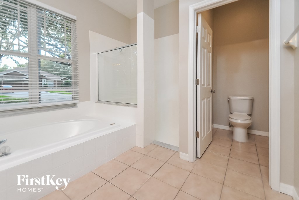 a bathroom with a tub and a toilet and a window