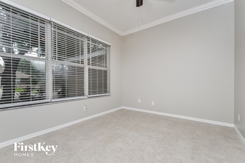a room with a large window with blinds and a white wall and flooring