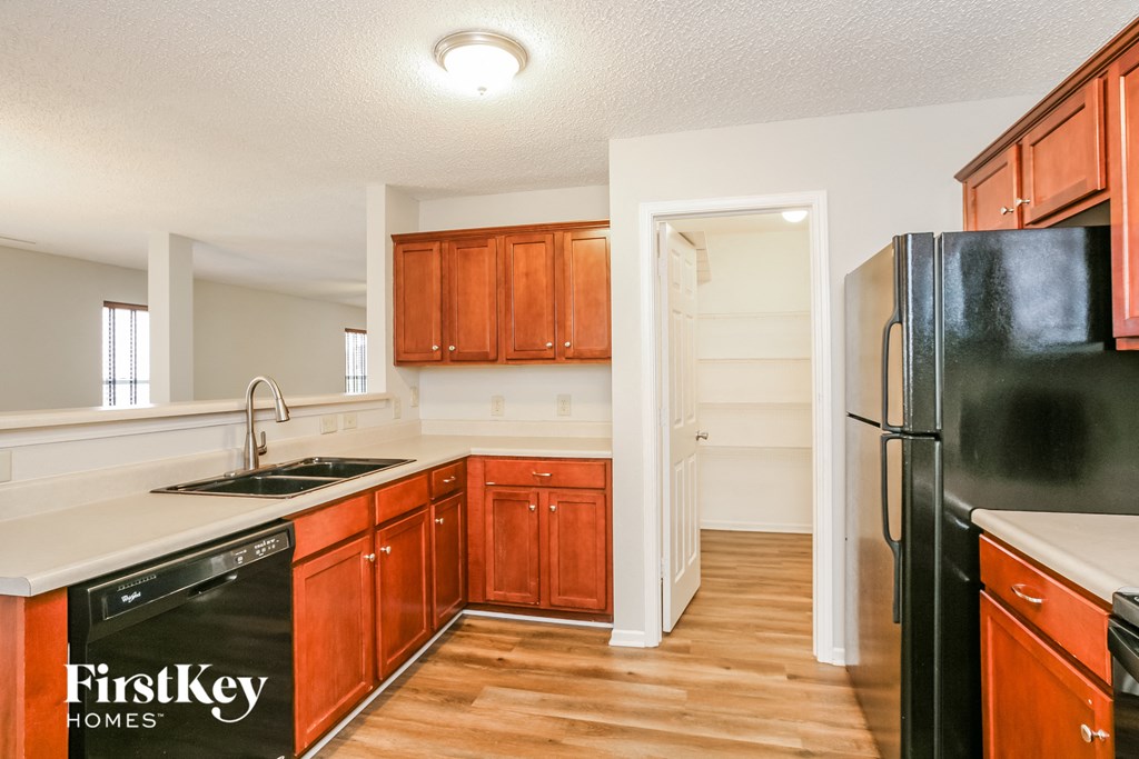 a kitchen with wooden cabinets and a black refrigerator