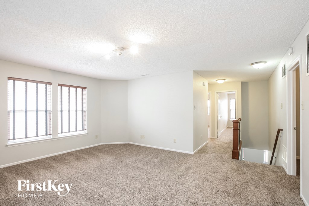 a spacious living room with carpeted flooring and large windows