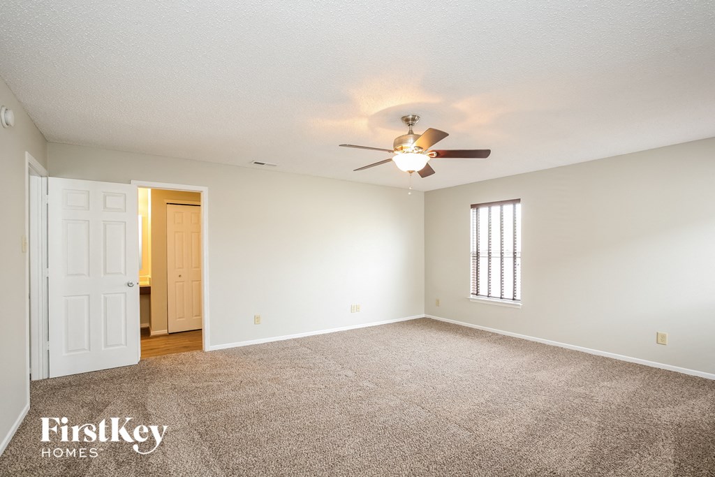 a living room with carpet and a ceiling fan