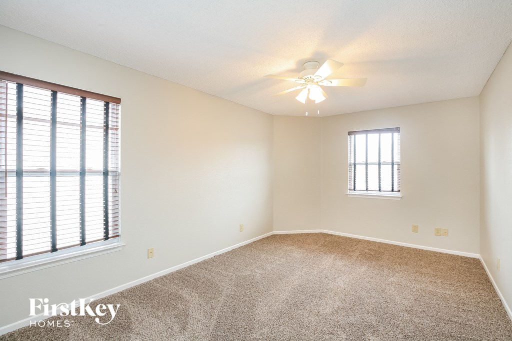 a spacious living room with carpet and a ceiling fan