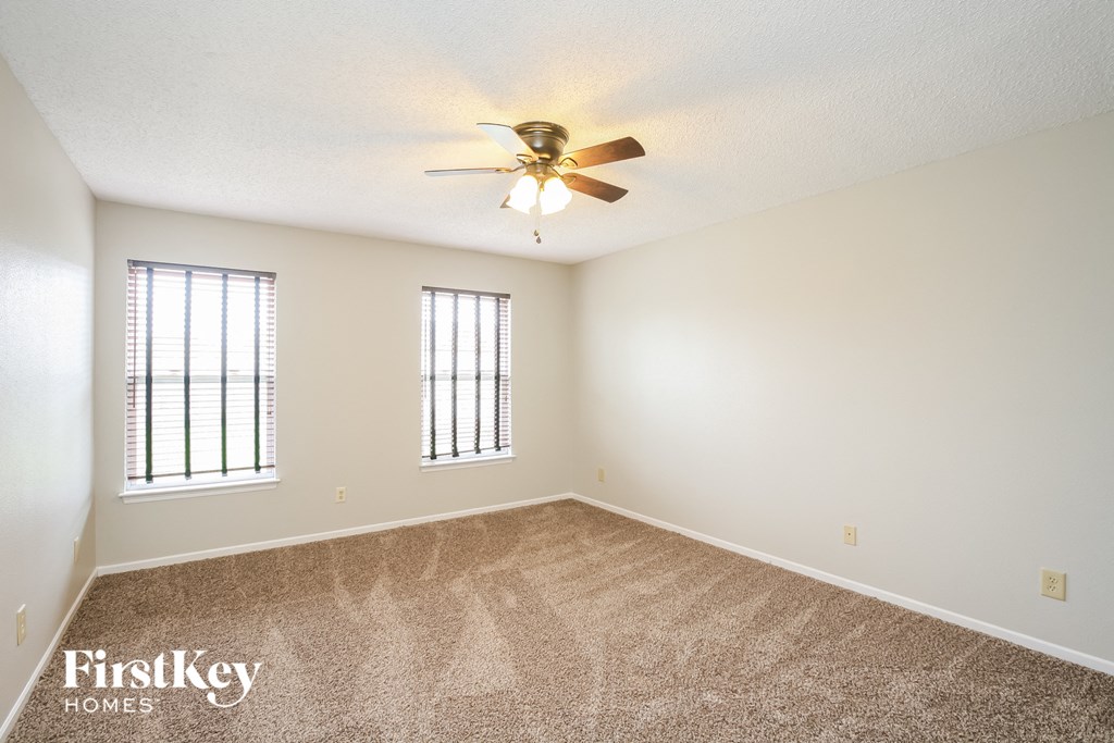 a spacious living room with carpet and a ceiling fan