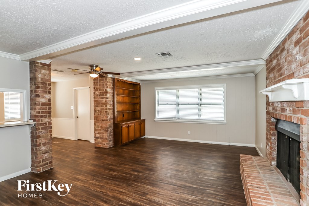 A room with a brick fireplace and wooden floors.