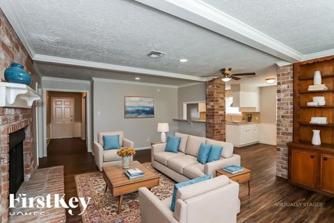 A living room with a brick fireplace and a painting on the wall.