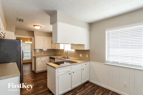 a kitchen with white cabinets and a large window