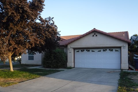 a white house with a white garage door and a tree