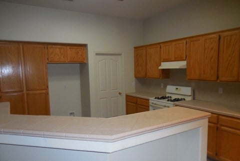 an empty kitchen with wooden cabinets and a white counter top