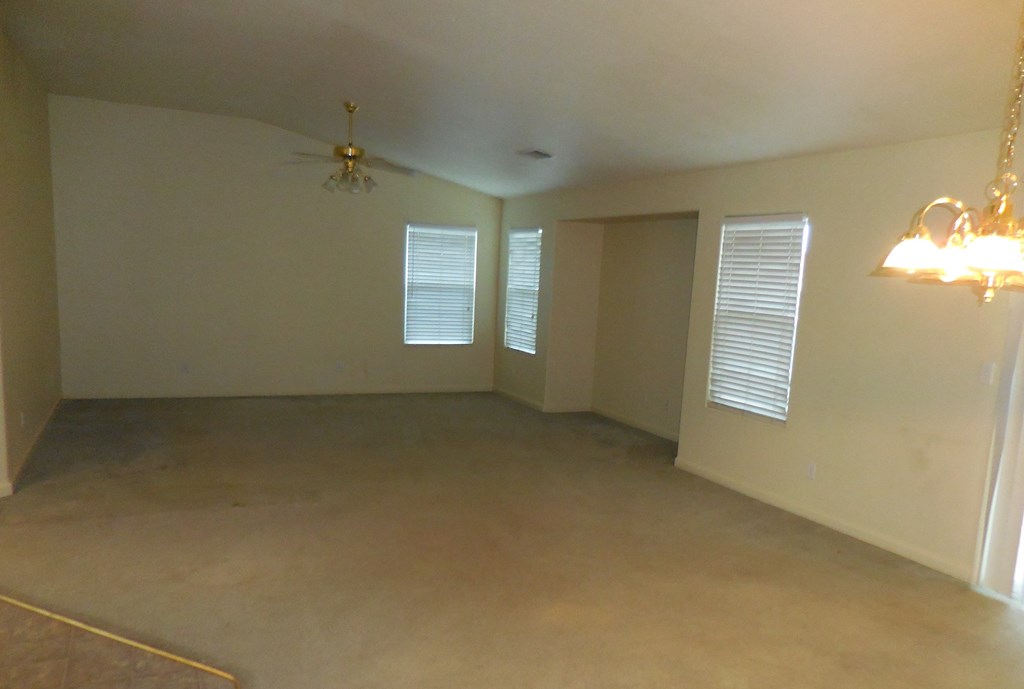 an empty living room with white walls and a ceiling fan