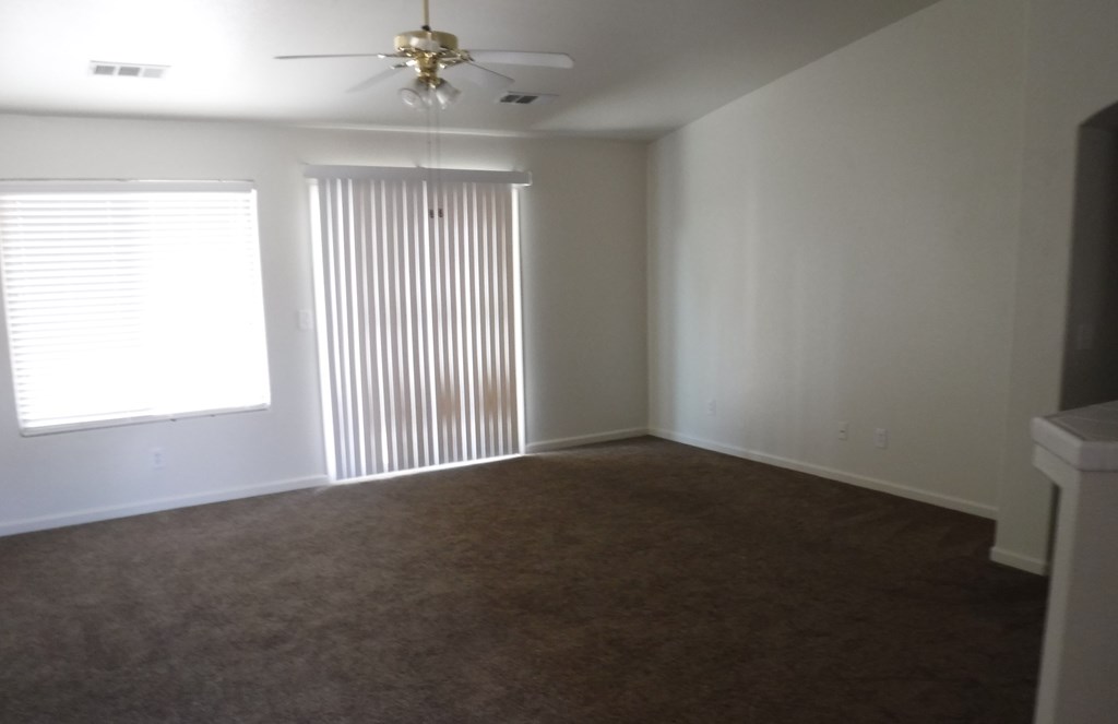 an empty living room with a ceiling fan and a window