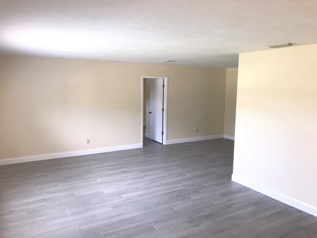 an empty living room with wood floors and white walls
