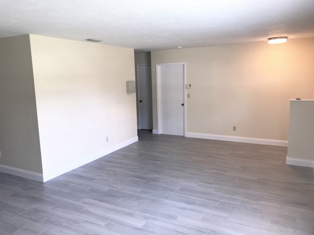 an empty living room with wood floors and white walls