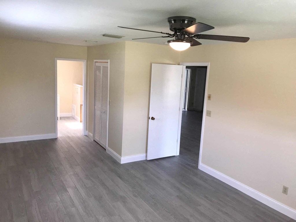 an empty living room with wood floors and a ceiling fan