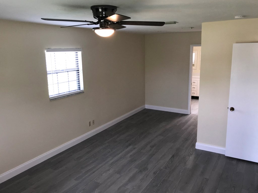 a living room with wood floors and a ceiling fan