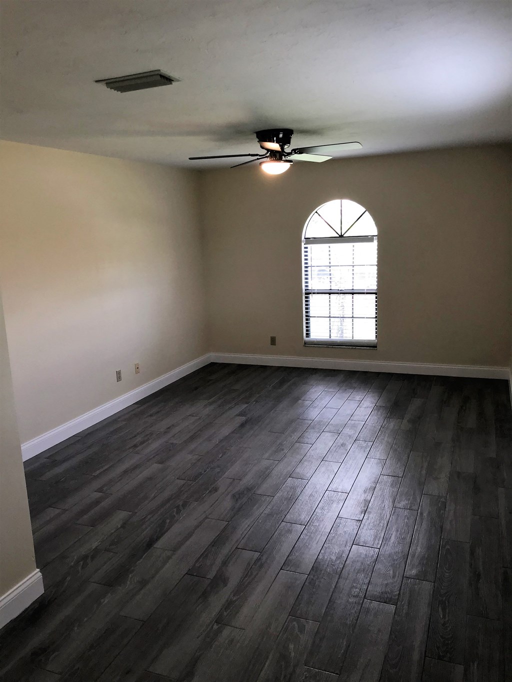 an empty living room with wood floors and a window