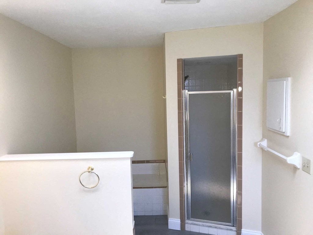 a bathroom with a shower and a white wall