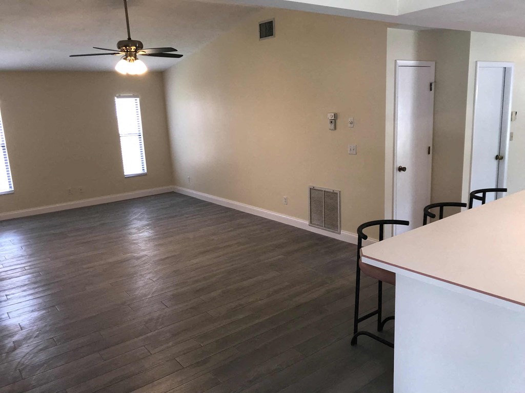 an empty living room with wood floors and a ceiling fan