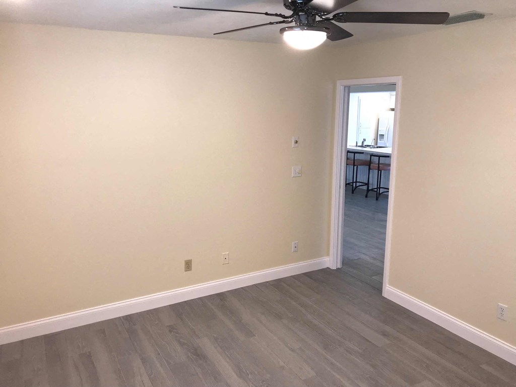 a living room with wood floors and a ceiling fan