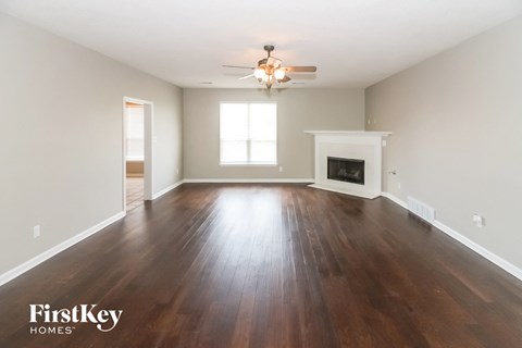 A spacious room with wooden floors and a fireplace.
