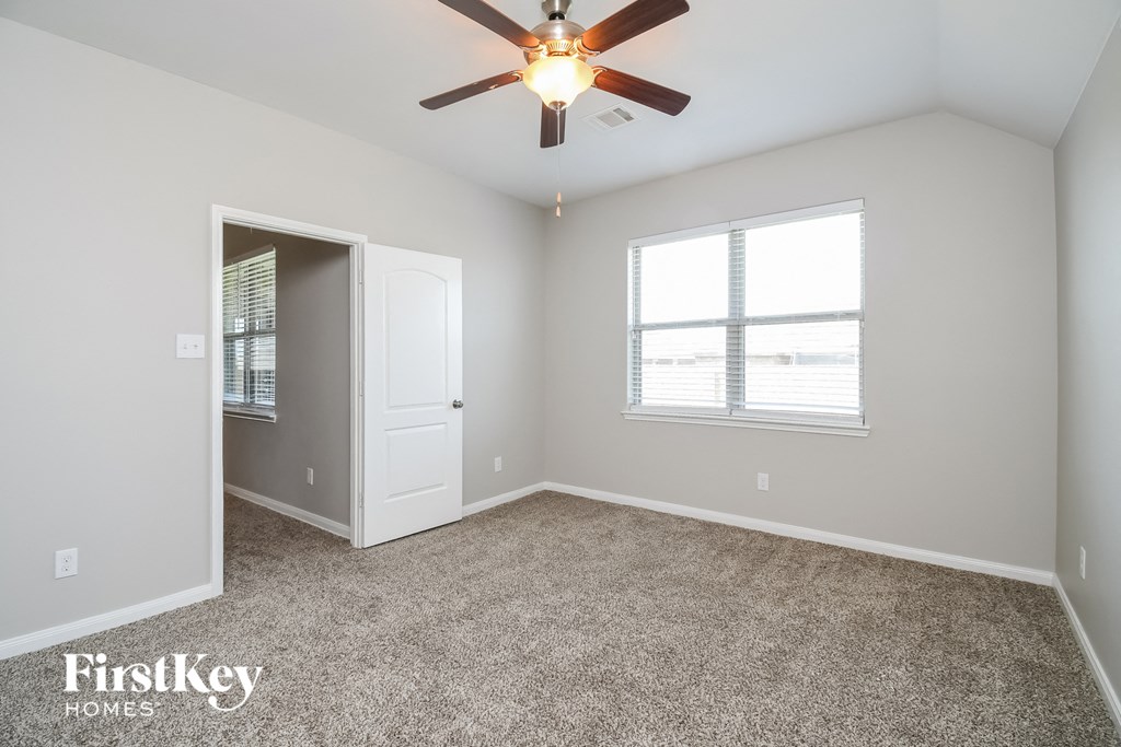 the master bedroom has carpet and a ceiling fan