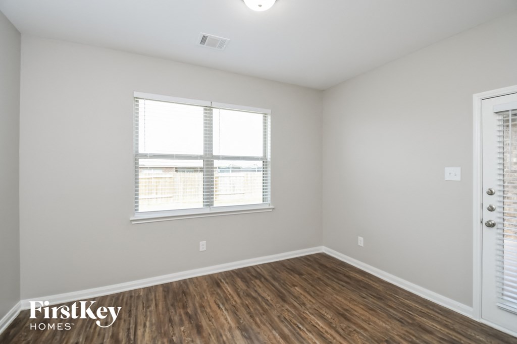 the living room of an apartment with wood flooring and two windows