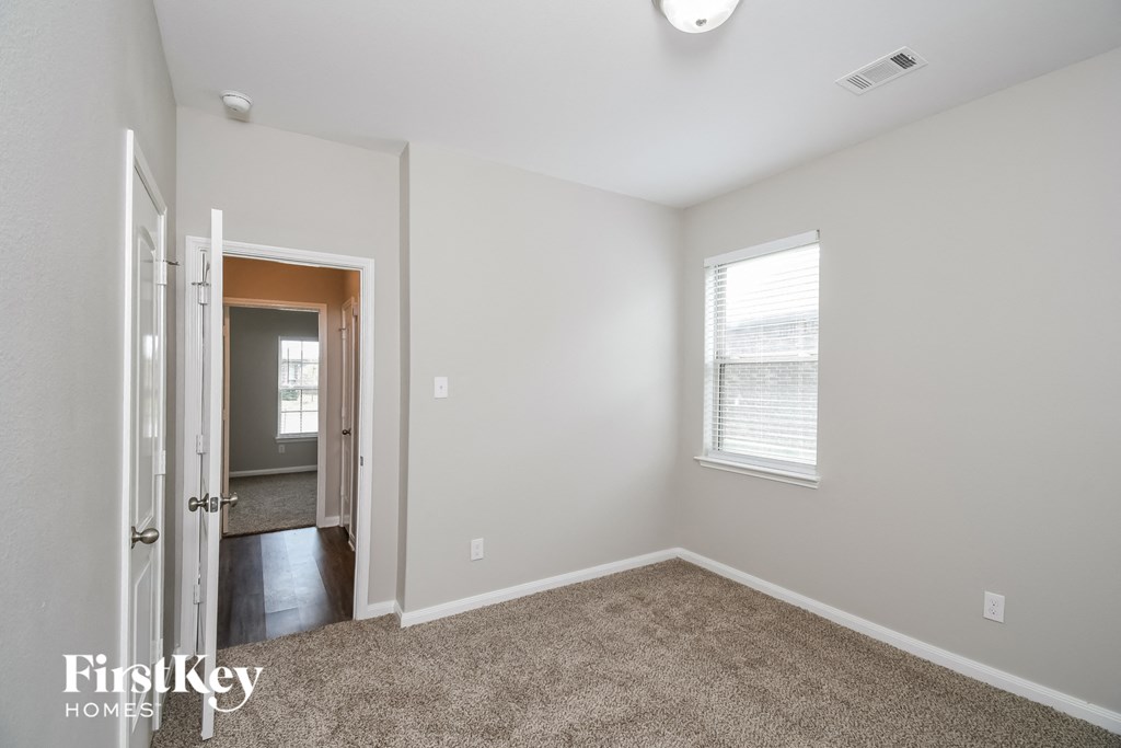 a bedroom with a carpeted floor and a door to a hallway