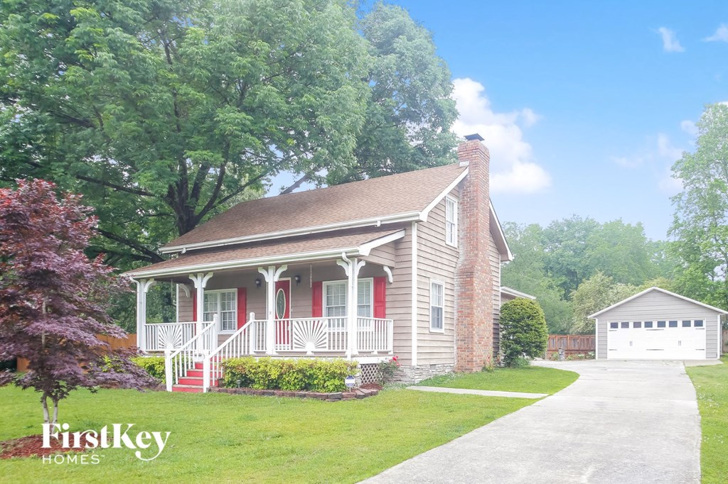 a small brick house with red doors and a white porch