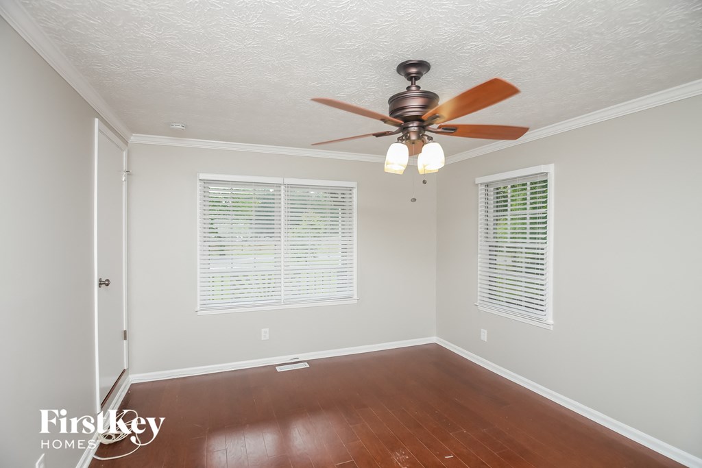a empty room with a ceiling fan and two windows