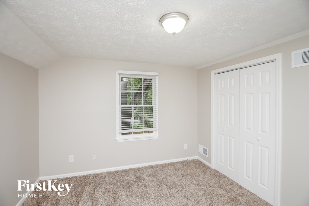 a bedroom with carpet and a white door and window