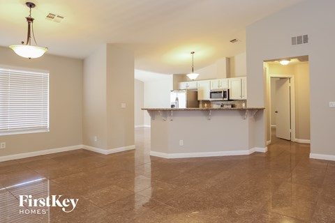 A spacious kitchen and living room with a tile floor and a bar area.